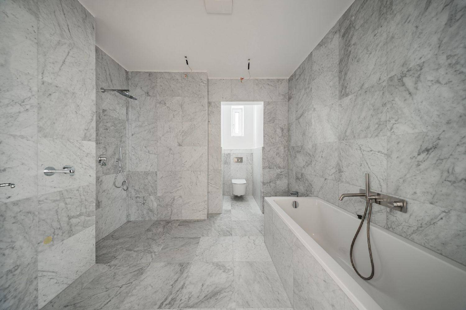 Modernes Badezimmer mit luxuriösen Marmorfliesen, einer geräumigen Walk-in-Dusche und einer eleganten Badewanne.