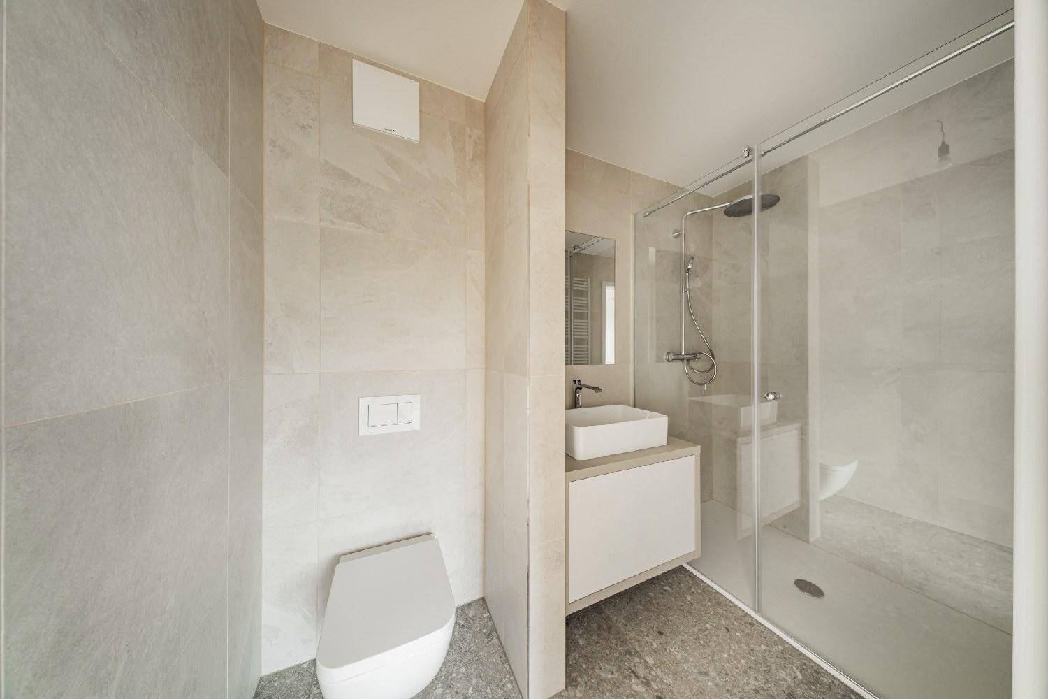 Modernes Badezimmer mit beigefarbenen Fliesen, ebenerdiger Dusche und wandhängendem WC.