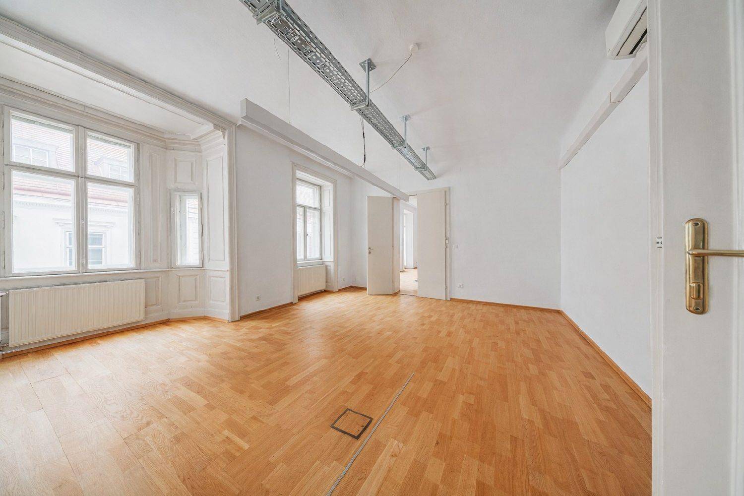 Großer, leerer Büroraum mit Erkerfenster, Holzboden und hohen Decken, ideal für gewerbliche Nutzung.
