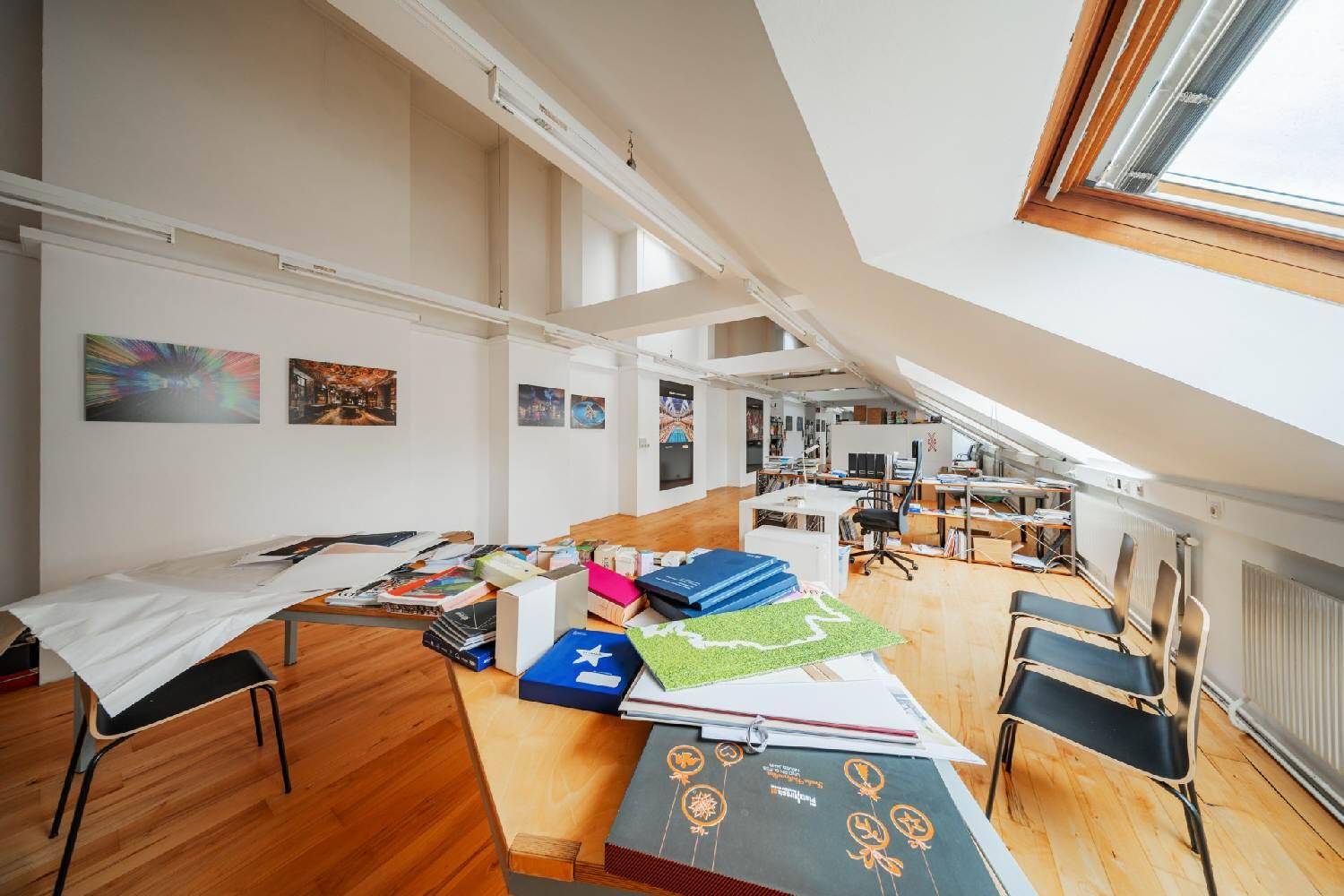 Helles Dachgeschossbüro mit Holzboden, Dachfenstern und Arbeitsbereichen, bietet viel Platz und Tageslicht.