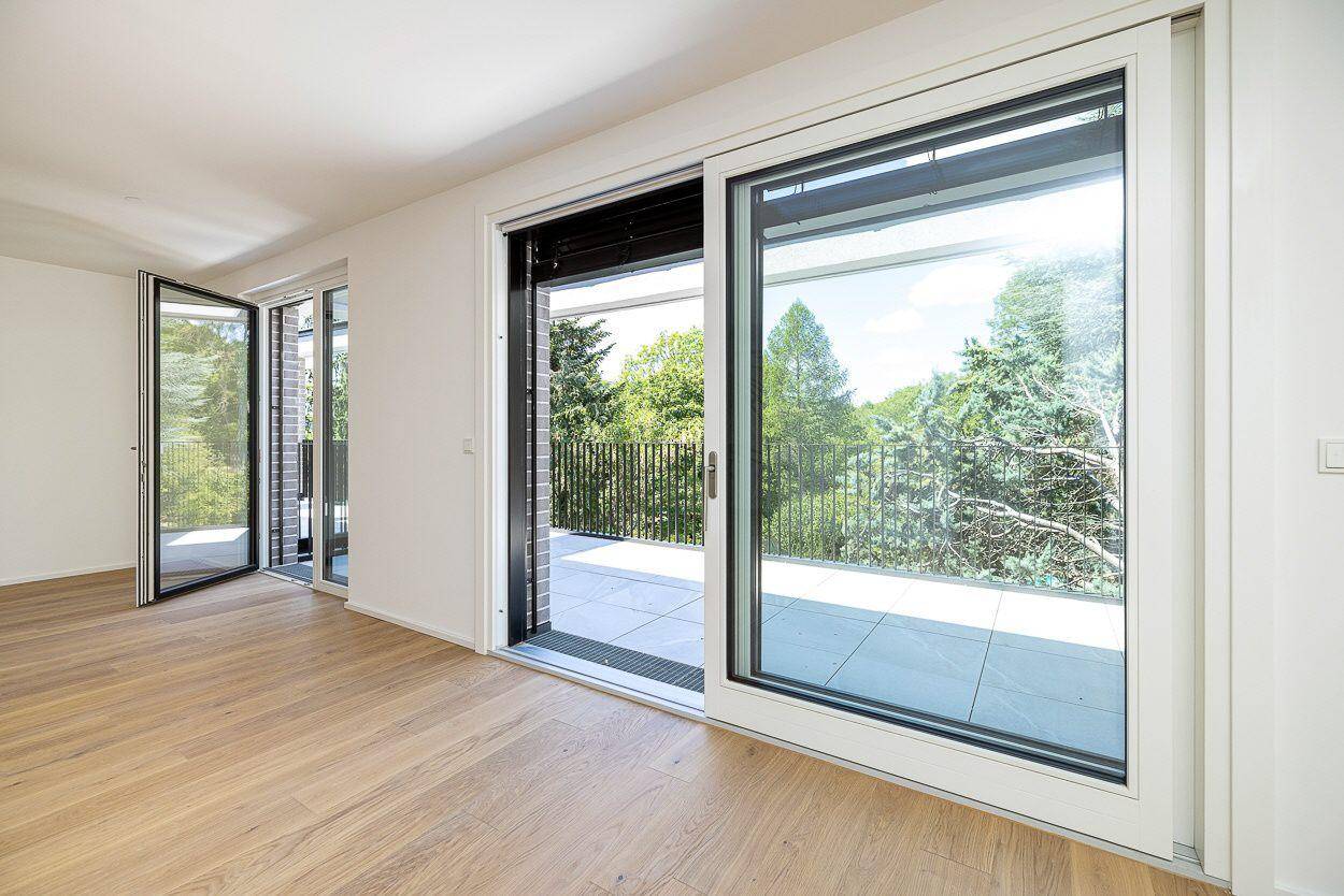 Große Fensterfront mit Schiebetüren, die viel Licht hereinlässt und Zugang zur Terrasse bietet.