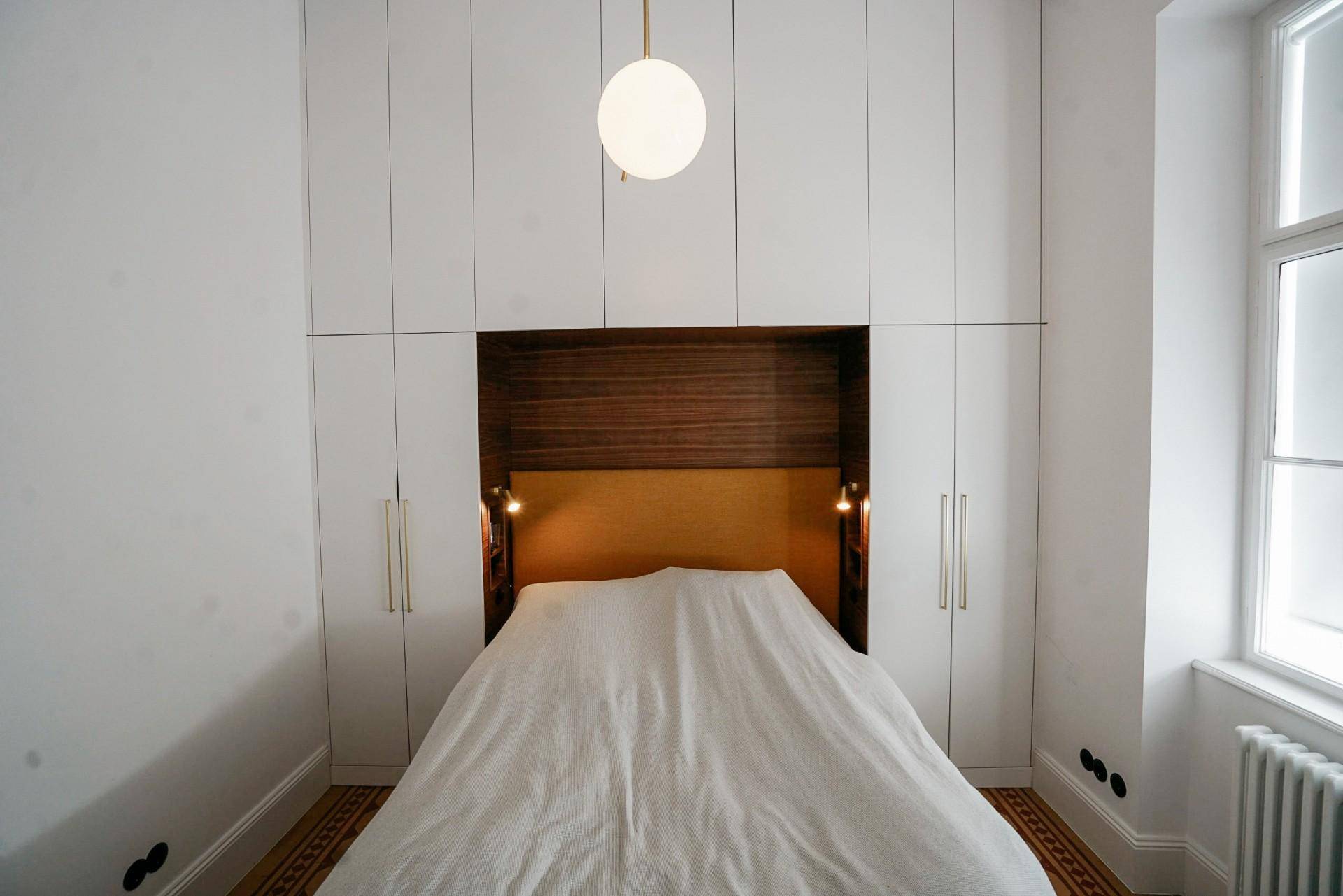 Schlafzimmer mit integrierten Einbauschränken, Holzakzenten und Parkettboden.