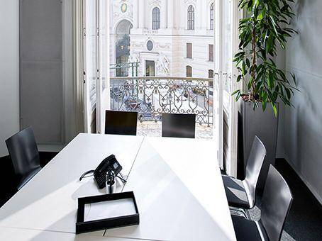 Büro oder Besprechungsraum mit Tisch, Stühlen und offenem Balkon mit Stadtblick.