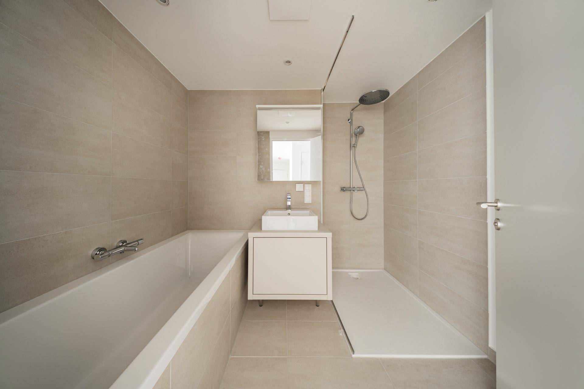 Modernes Badezimmer mit Badewanne, ebenerdiger Dusche und beigefarbenen Fliesen.