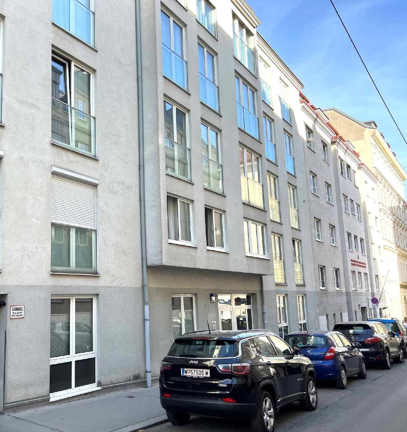 Moderne Gebäudefassade mit großen Fenstern und Balkonen an einer städtischen Straße.