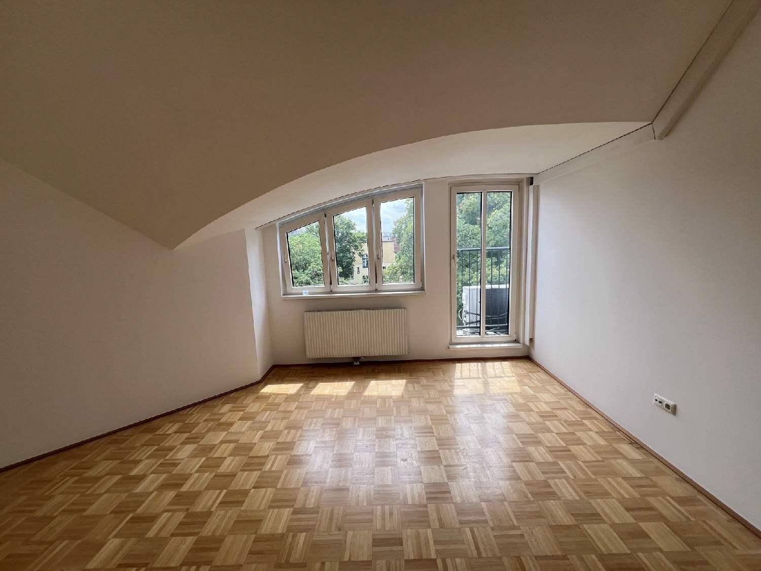Geräumiges Zimmer mit Fischgrätparkett, Dachschrägen und Blick ins Grüne.