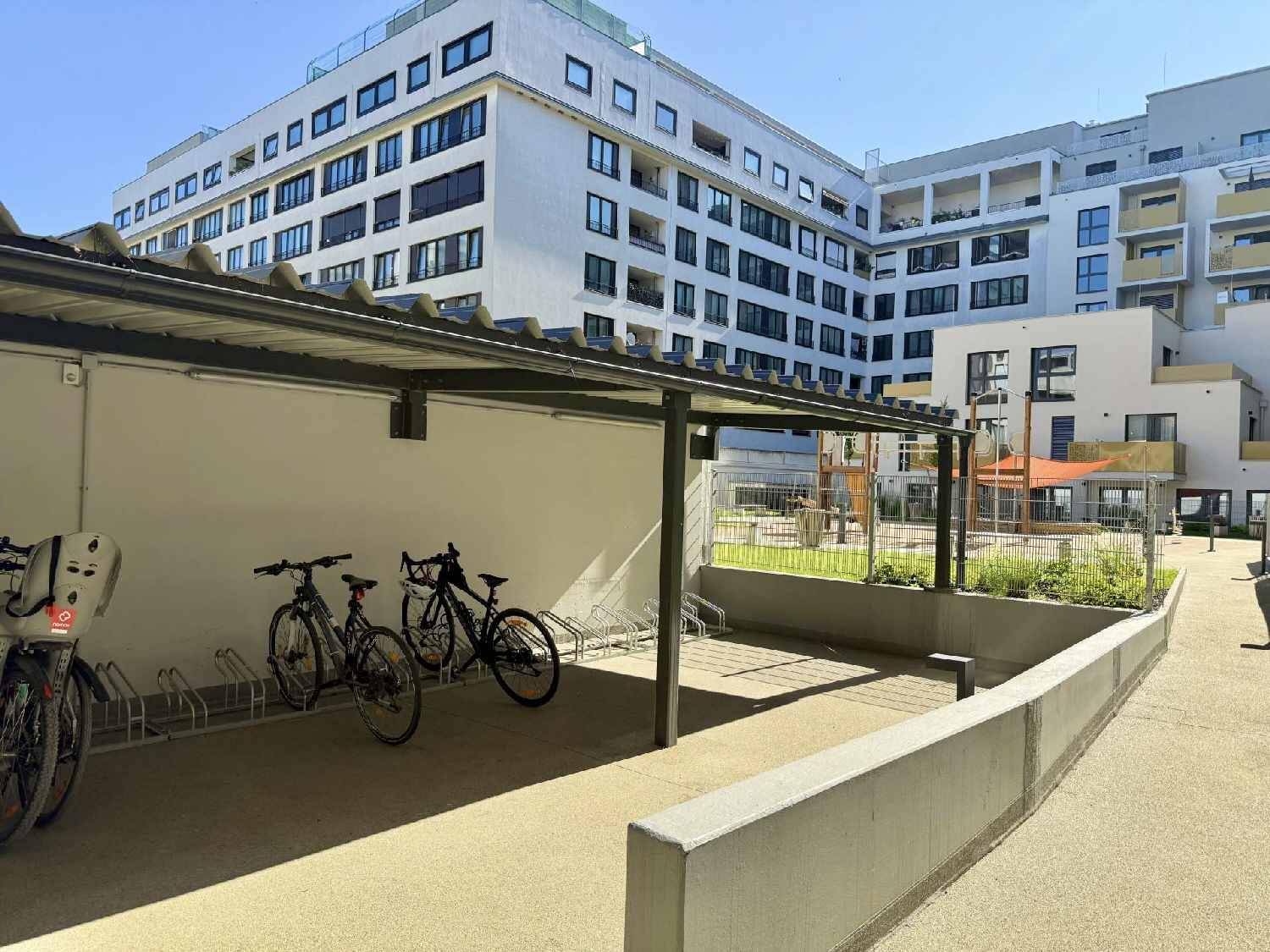 Überdachter Fahrradabstellplatz im Innenhof eines modernen Wohnkomplexes.