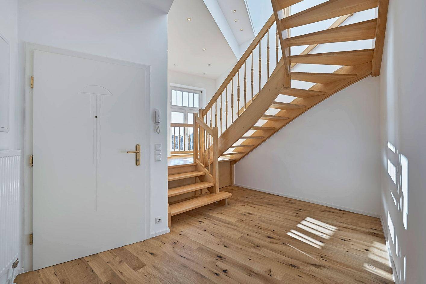 Heller Eingangsbereich mit Holztreppe und Holzboden.