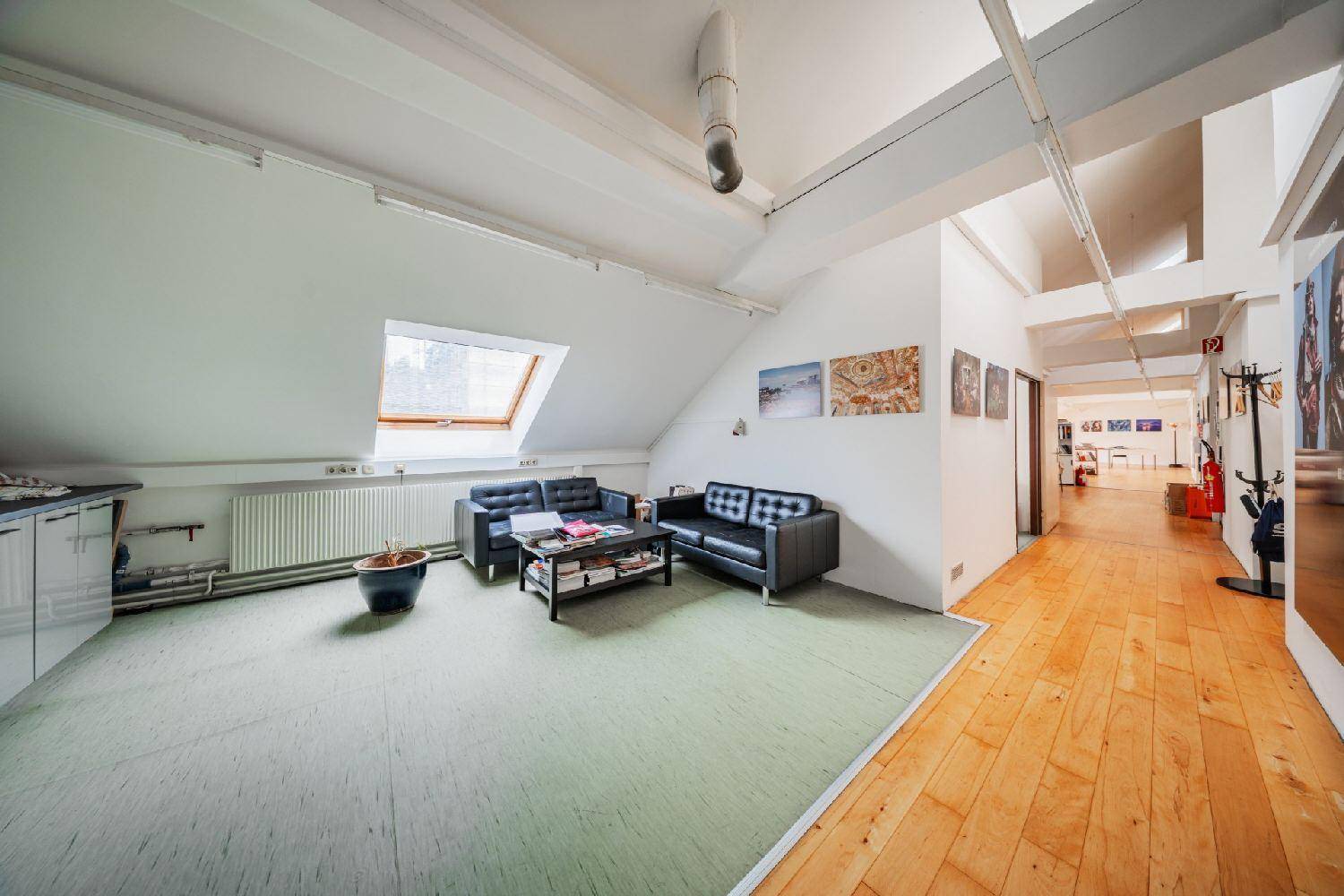 Entspannungsbereich im Dachgeschoss mit Sofas, Couchtisch und grünem Bodenbelag, lädt zum Verweilen ein.