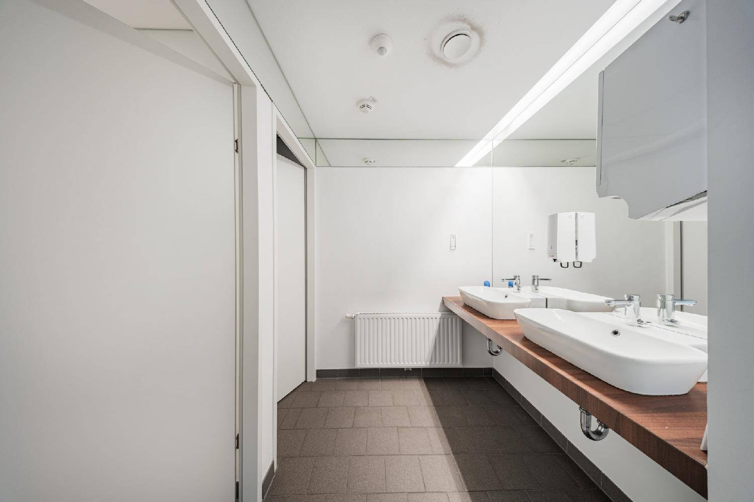 Modernes Badezimmer mit Doppelwaschbecken, Holzplatte und großem Spiegel.