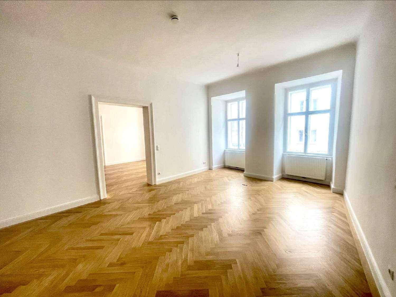 Helles Wohnzimmer mit klassischem Fischgrätparkett, hohen Decken und großen Fenstern mit Blick nach draußen.