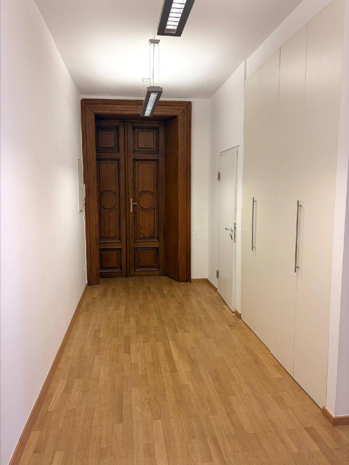 Langer Flur mit eleganten Holztüren am Ende und praktischen Einbauschränken an der Seite.