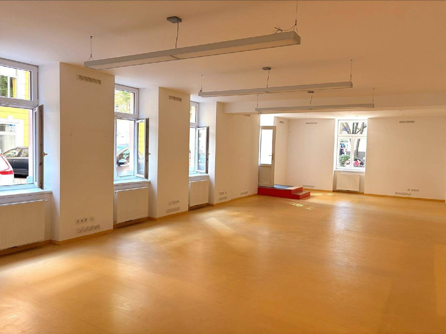 Weitläufiger, heller Gewerberaum mit vielen Fenstern, die viel Tageslicht hereinlassen, und einem hellen Boden.
