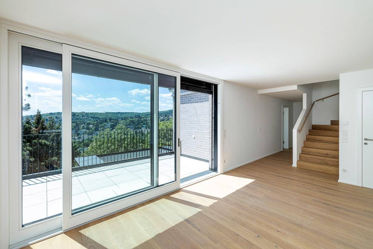 Helles Wohnzimmer mit großen Schiebetüren, Holzboden und weitem Ausblick ins Grüne.