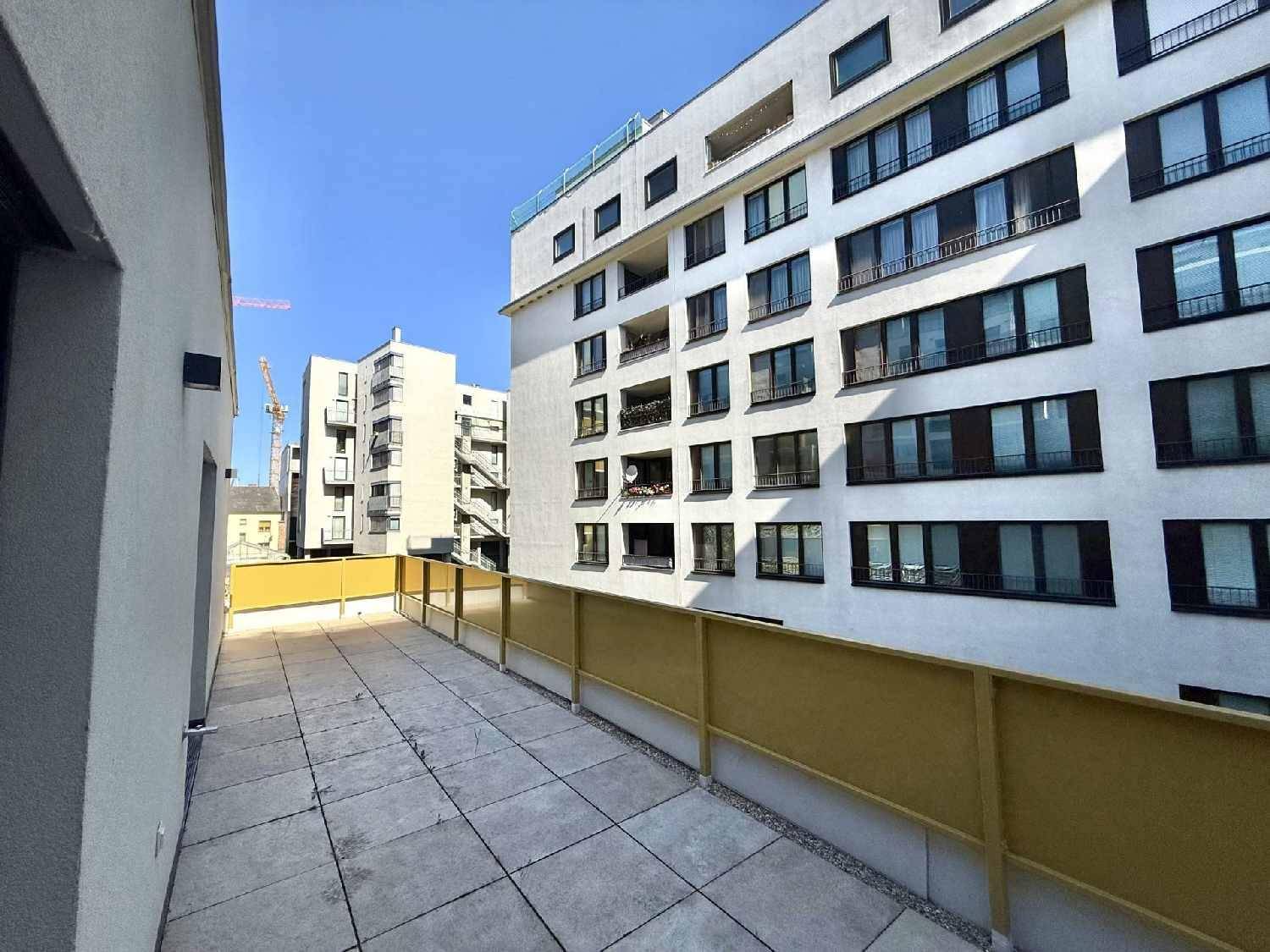 Geräumige Terrasse mit Blick auf moderne Wohngebäude und den blauen Himmel.