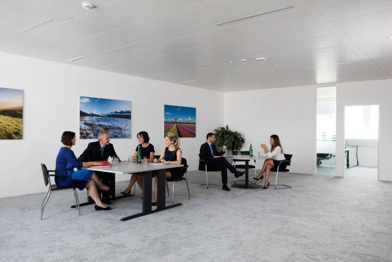 Heller und moderner Loungebereich in einem Bürogebäude mit mehreren Personen an Tischen.