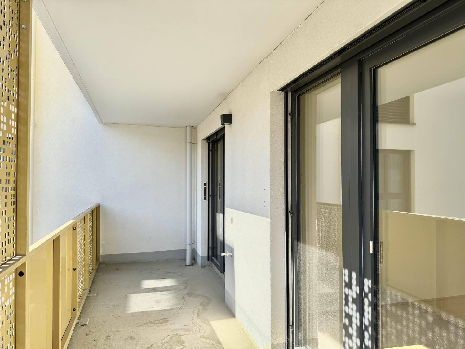 Langer Balkon mit moderner Brüstung und Zugang durch große Glastüren.