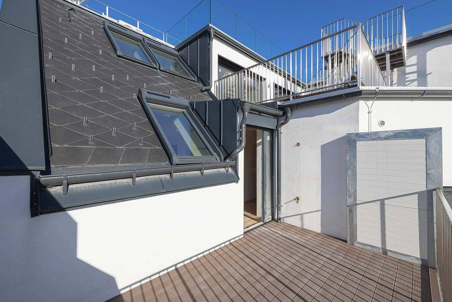 Geräumige Dachterrasse mit Holzboden und Blick auf die Umgebung, ideal für Entspannung im Freien.