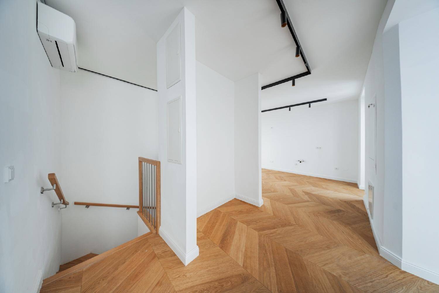 Moderner Flur mit Holztreppe und Fischgrätparkett, ausgestattet mit Klimaanlage.
