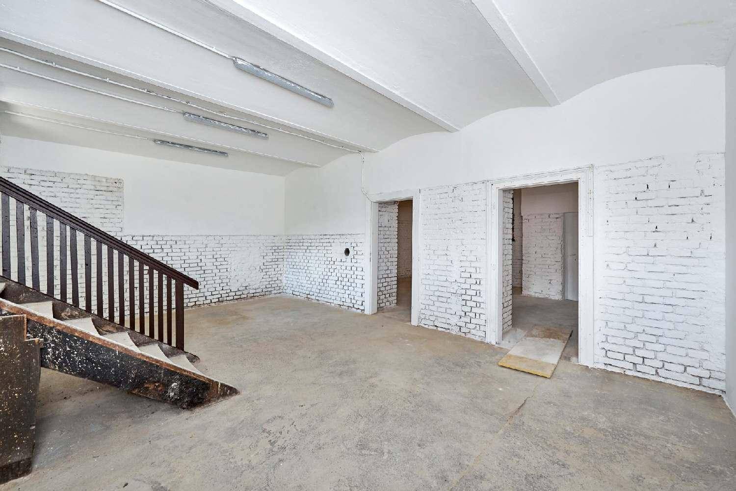 Geräumiger Lagerraum mit dunkler Holztreppe und zwei offenen Durchgängen zu weiteren Bereichen.