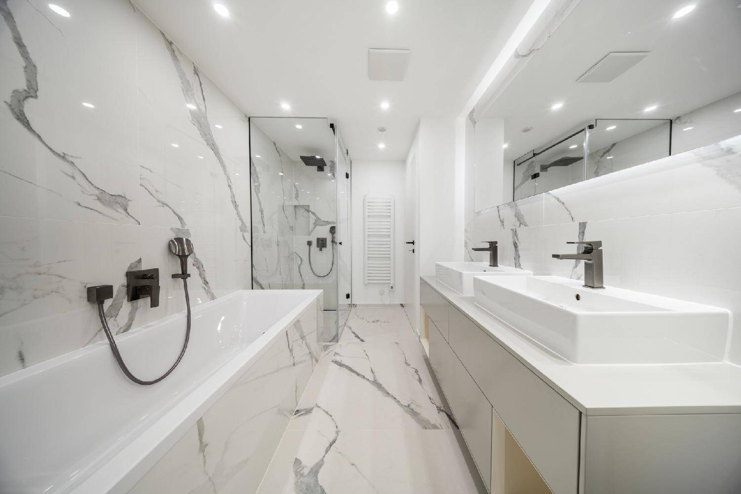 Modernes Badezimmer mit luxuriösen Marmorfliesen, Doppelwaschbecken und einer begehbaren Dusche.