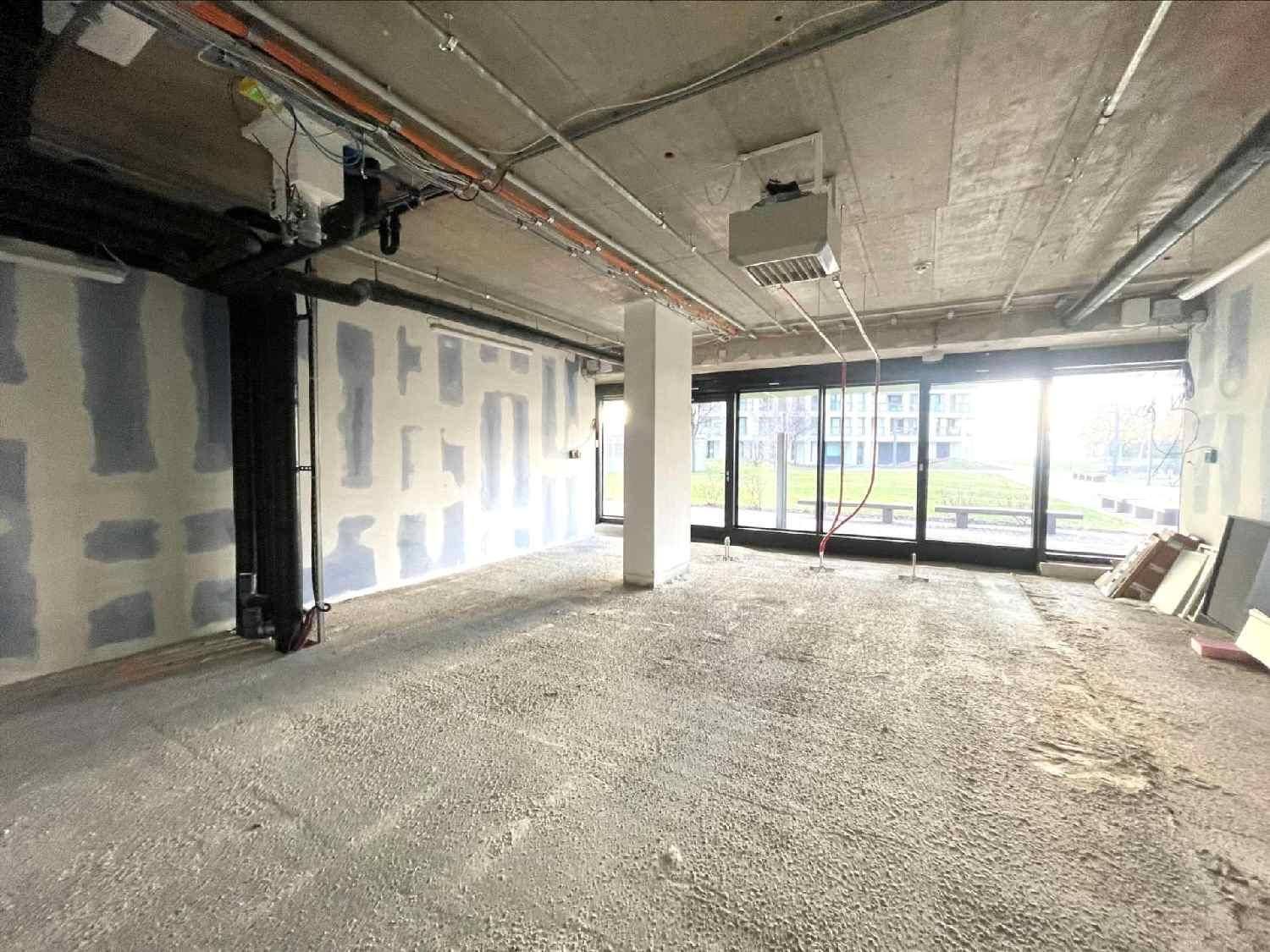 Heller, unmöblierter Gewerberaum mit unverputzten Wänden und sichtbaren Installationen an der Decke.