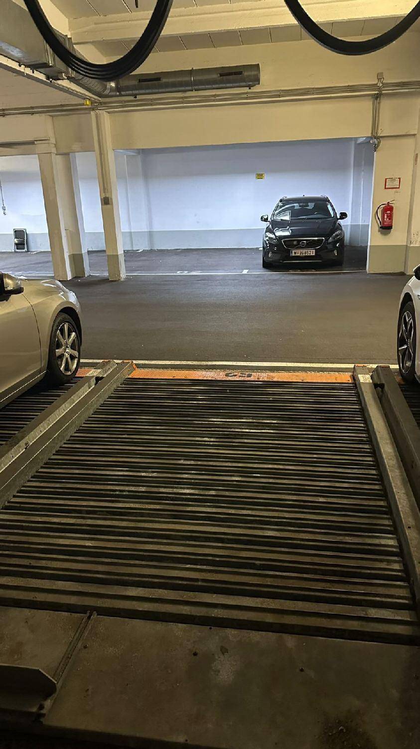 Leere mechanische Parkplattform in einer Tiefgarage mit einem Auto im Hintergrund.