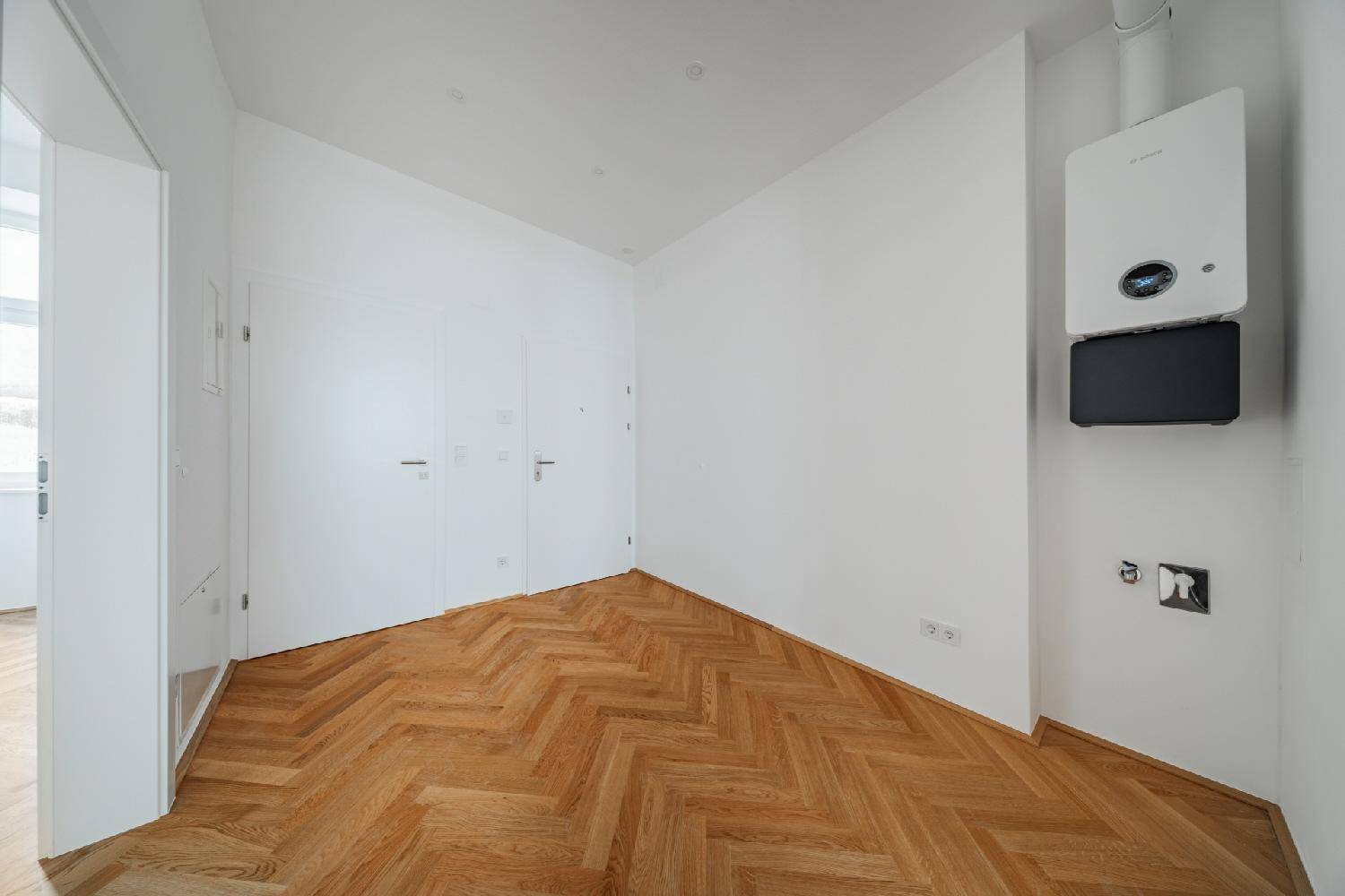 Bereich mit Fischgrätparkett und einem modernen Heizkessel, ideal als Hauswirtschaftsraum.