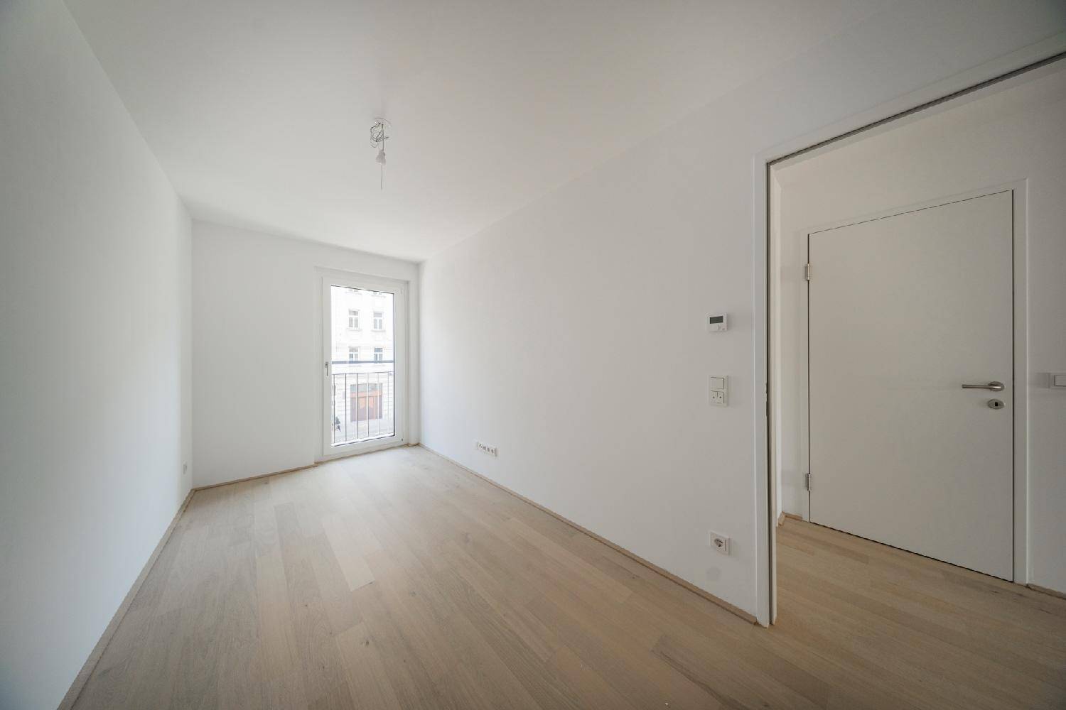 Helles Zimmer mit Parkettboden und französischem Balkon, ideal als Schlaf- oder Arbeitszimmer.