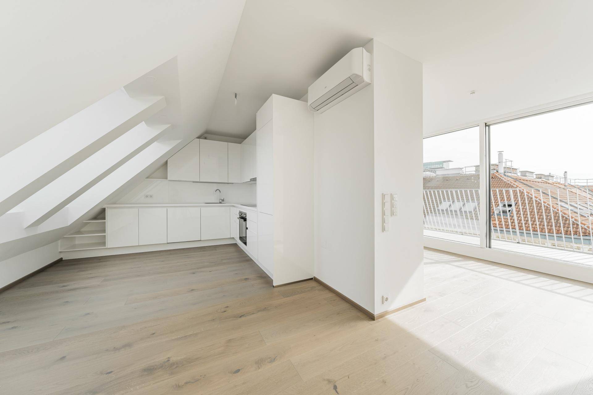 Offener Wohnbereich mit integrierter Küche, Holzboden und Zugang zur Dachterrasse.