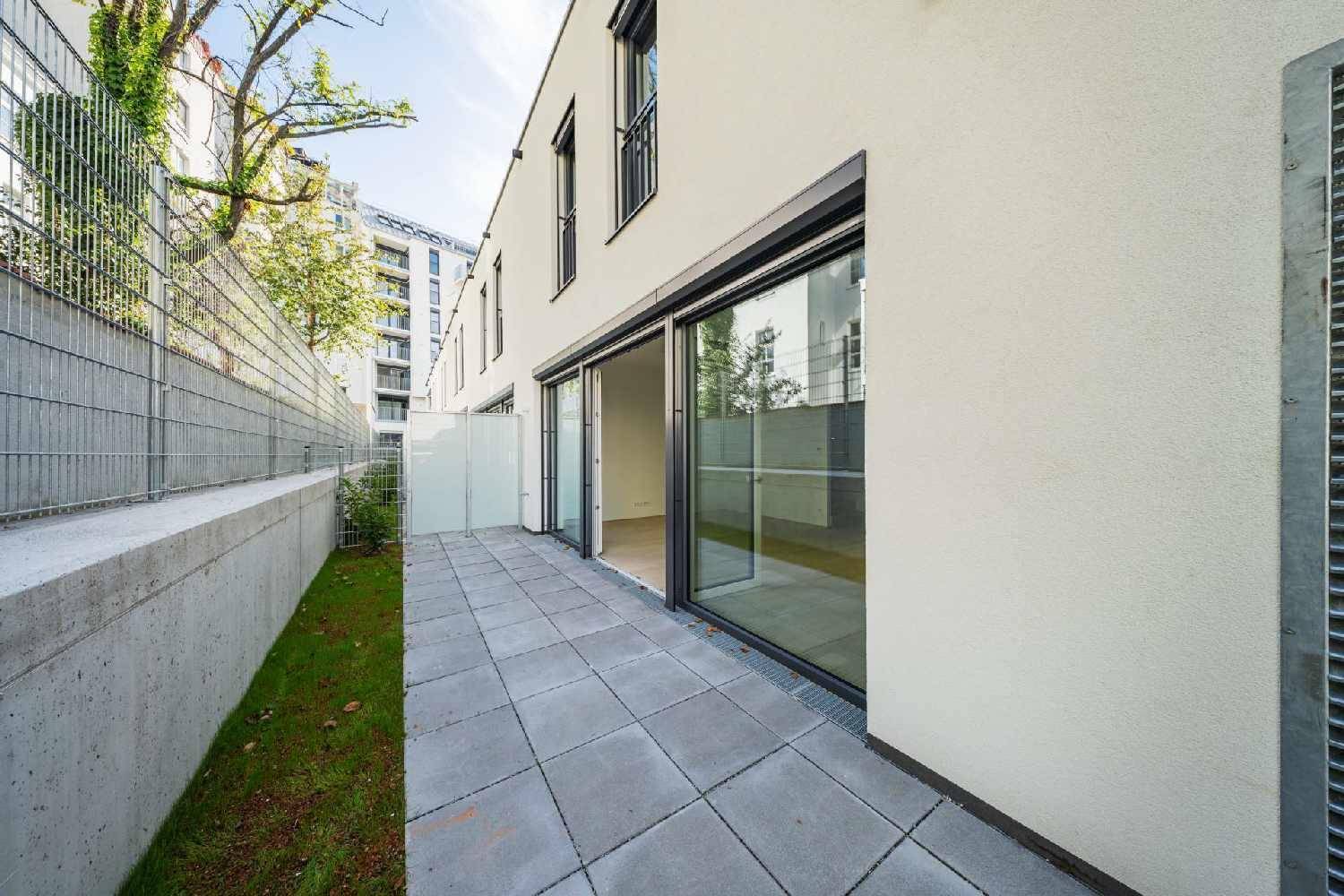 Breite gepflasterte Terrasse mit Schiebetüren und Blick auf die Umgebung.