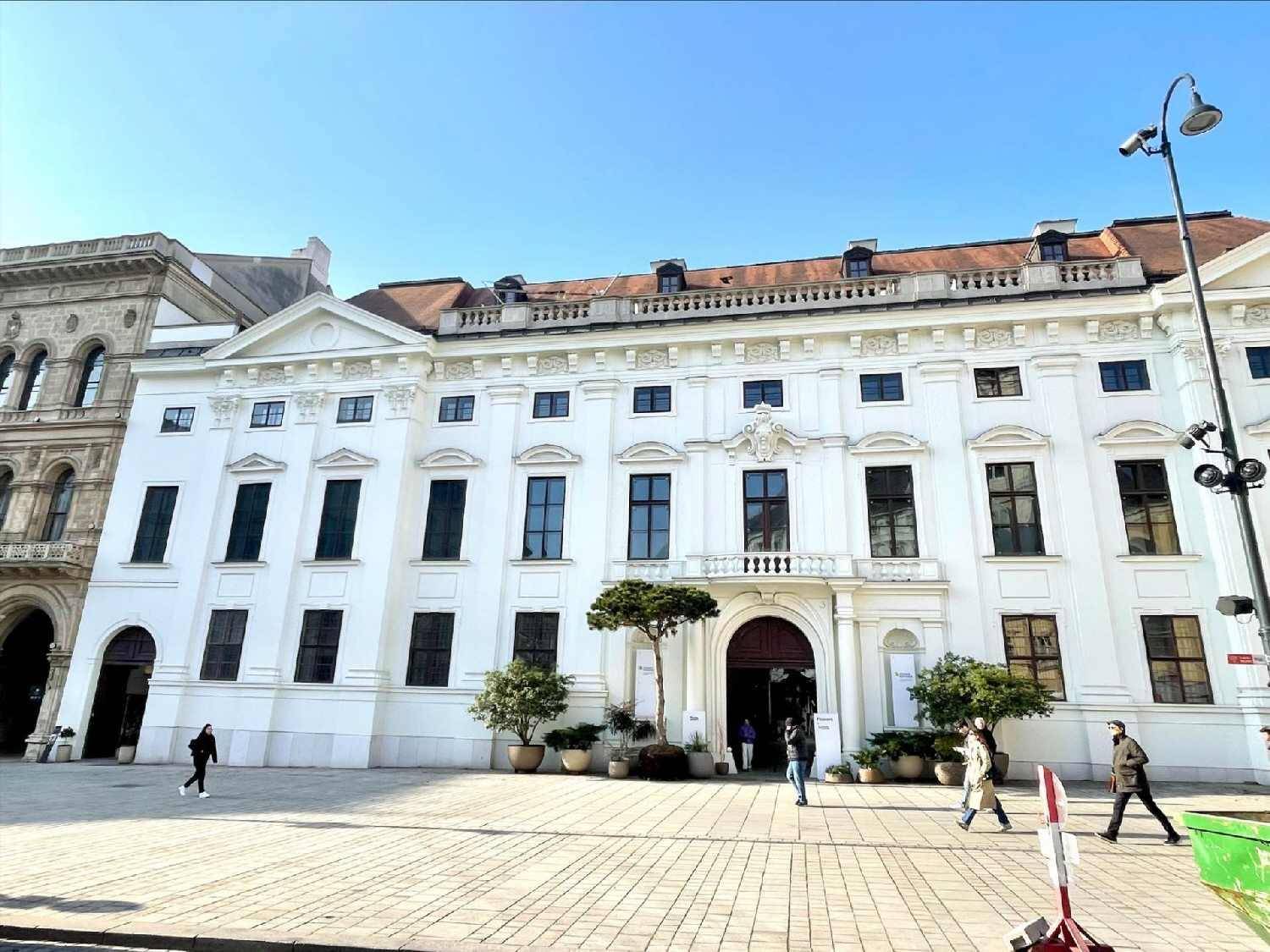 Elegantes historisches Gebäude mit weißer Fassade, großen Fenstern und klassischer Architektur.