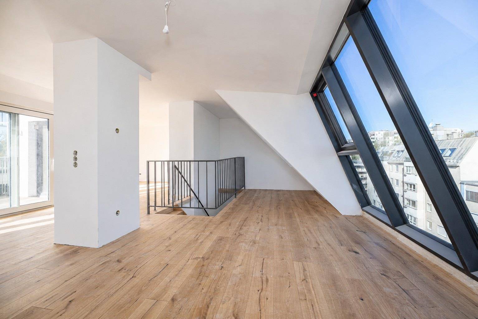 Lichtdurchfluteter Wohnbereich mit schrägen Fenstern, Holzboden und moderner Architektur.