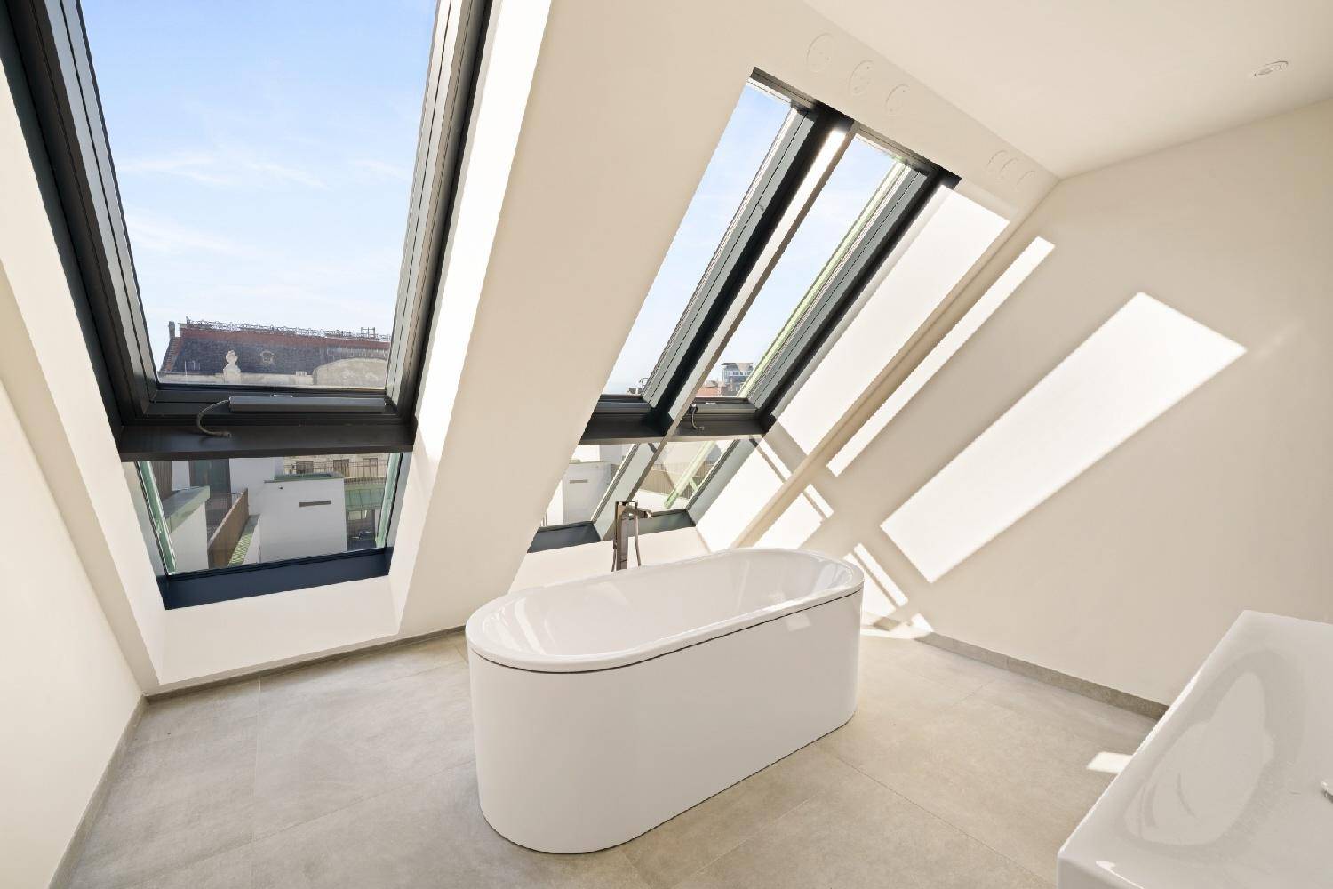 Modernes Badezimmer mit freistehender Badewanne und großen Dachfenstern für viel Licht.