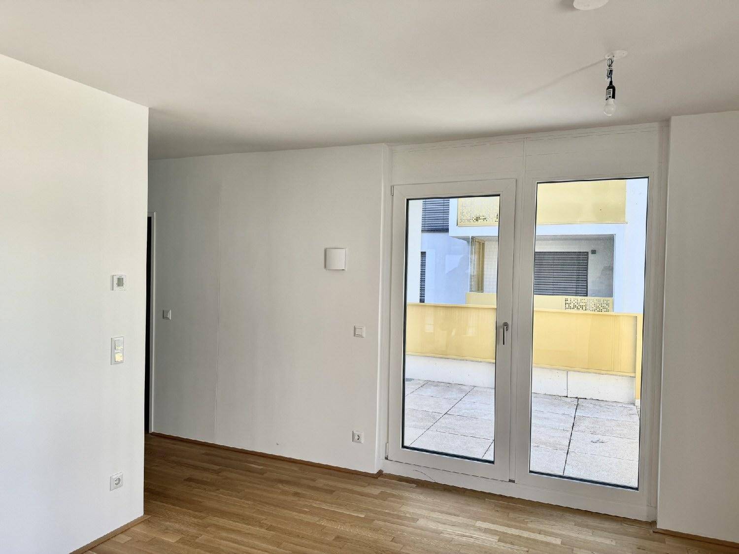 Heller Wohnbereich mit Parkettboden und direktem Zugang zu einer privaten Terrasse.