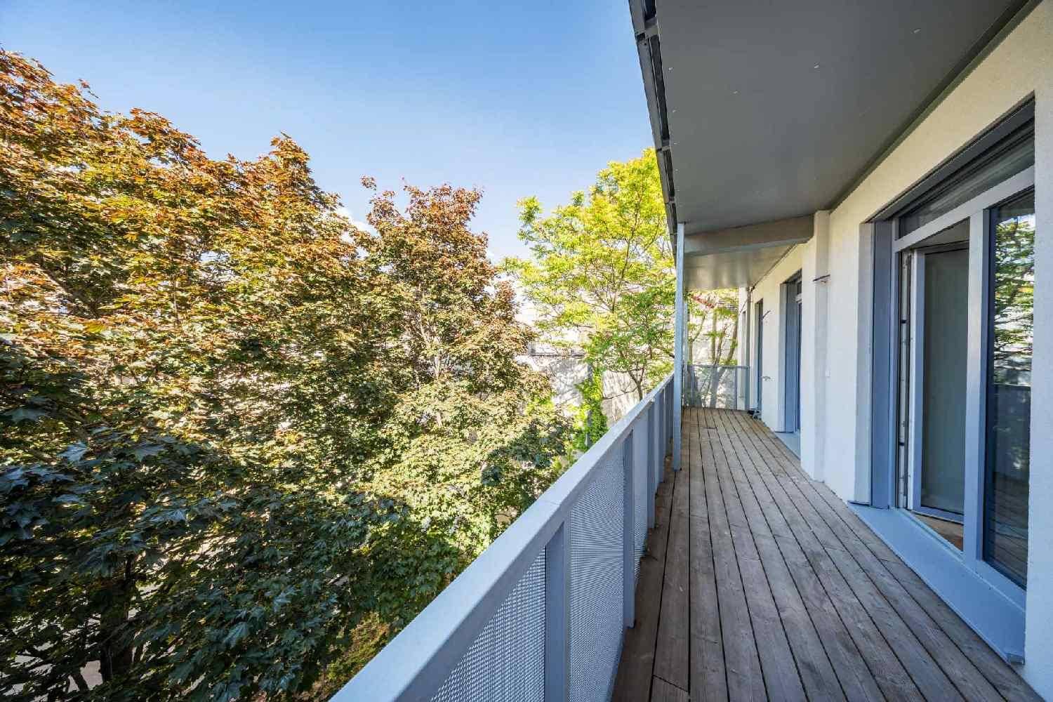 Langer Balkon mit Holzbelag und Blick auf grüne Bäume, ideal zum Entspannen im Freien.