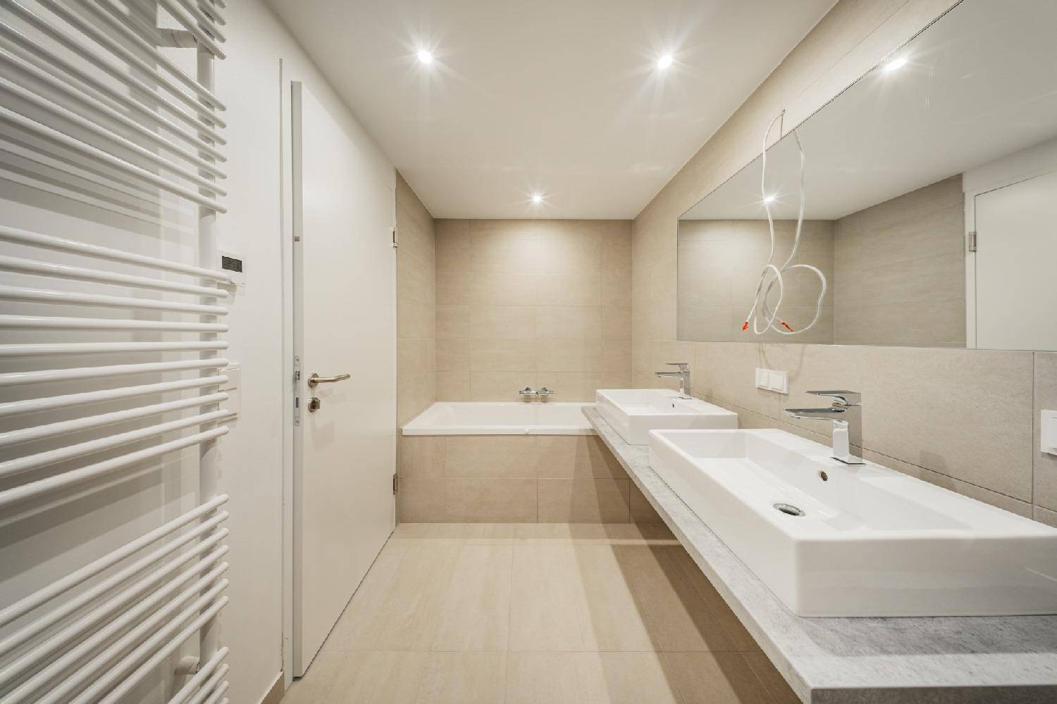 Modernes Badezimmer mit Doppelwaschbecken, Badewanne und beheiztem Handtuchhalter.