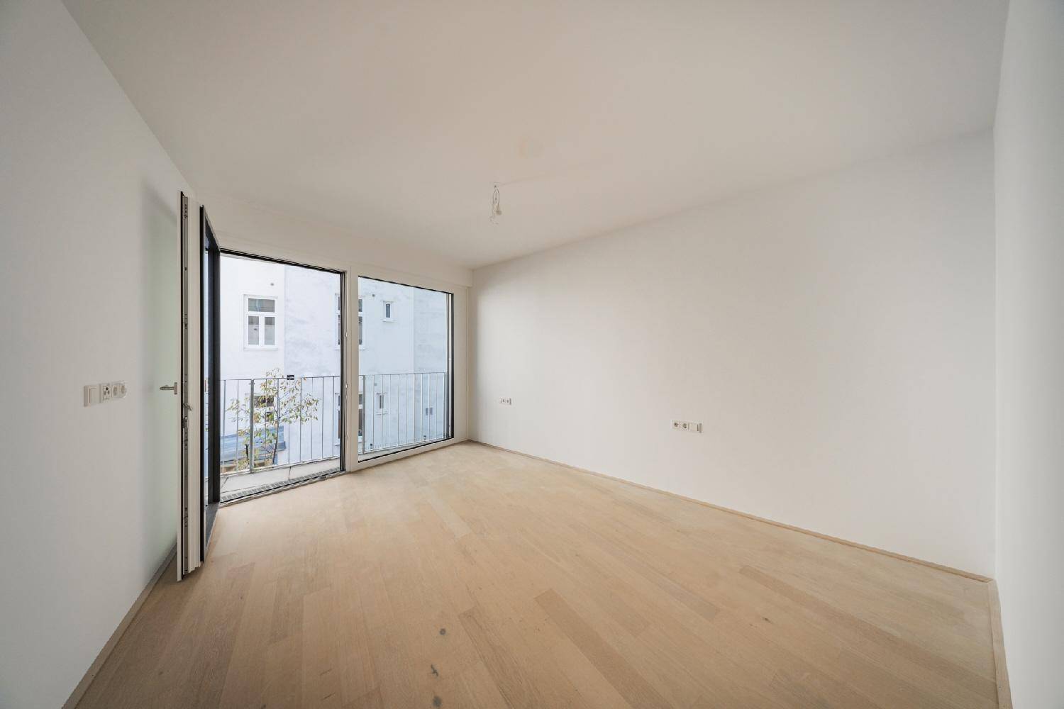 Helles Schlafzimmer mit Holzboden und Zugang zu einem französischen Balkon mit Stadtblick.