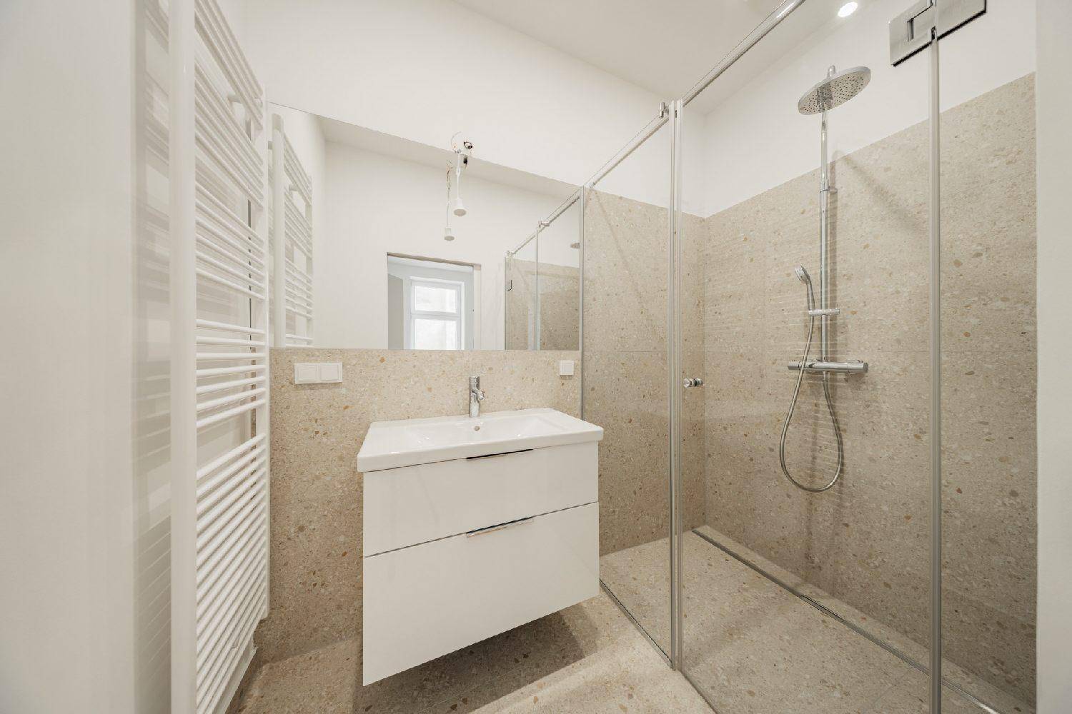 Elegantes Badezimmer mit großer begehbarer Dusche, modernem Waschtisch und Spiegel.