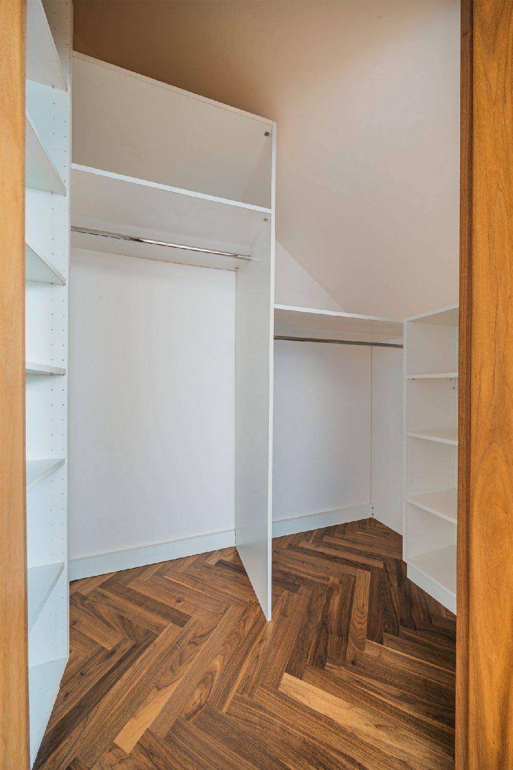 Praktischer begehbarer Kleiderschrank mit Regalsystem und Fischgrätparkett.