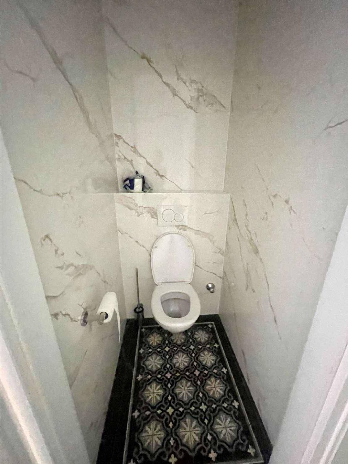 Modernes WC mit eleganten Marmor-Optik-Fliesen an den Wänden und gemustertem Boden.