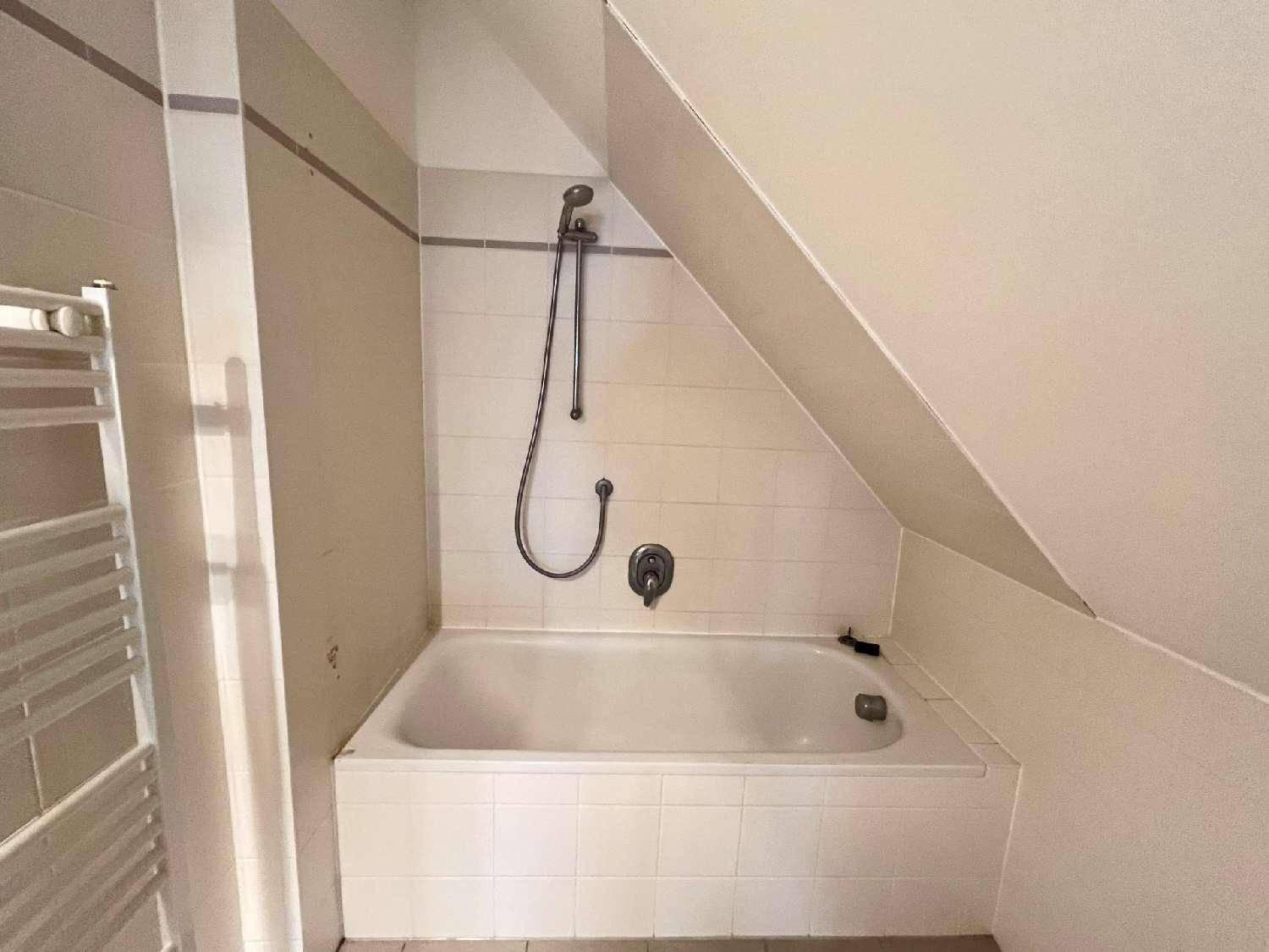 Nahaufnahme der Badewanne mit Duscharmatur in einem gefliesten Badezimmer.