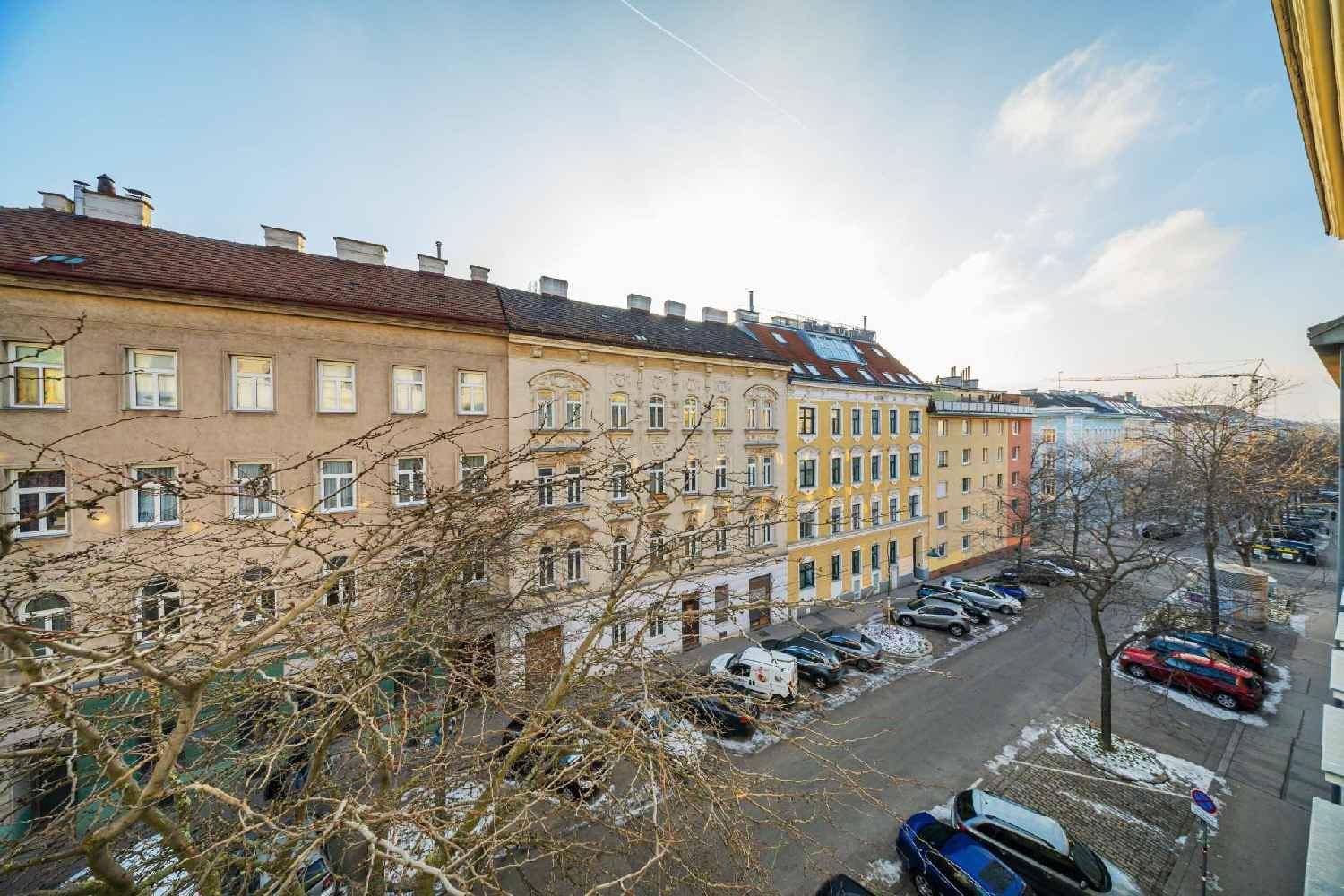 Blick auf eine belebte Straße mit parkenden Autos und historischen Gebäuden in der Stadt.