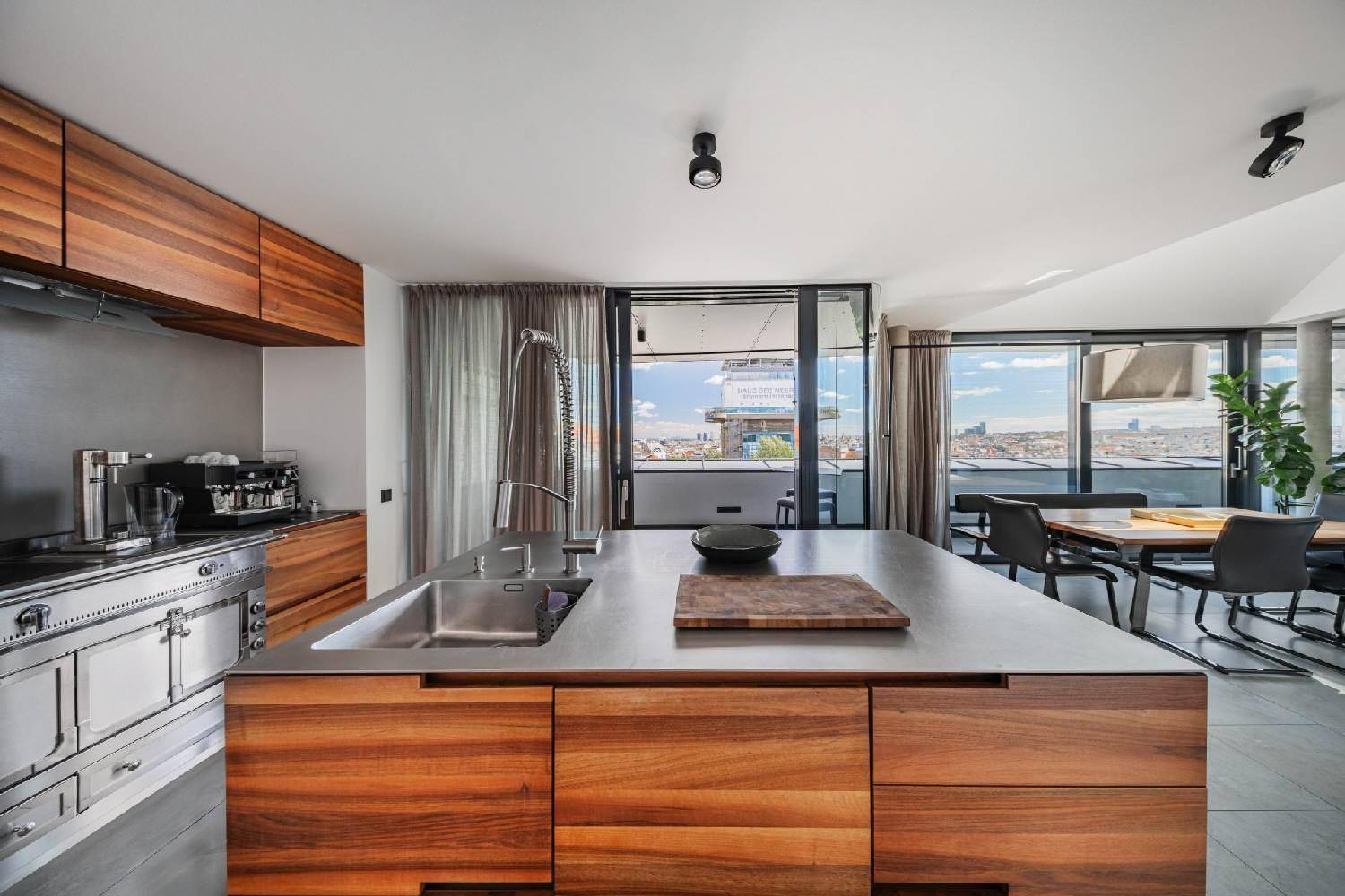 Moderne Holzküche mit Kücheninsel, Edelstahlgeräten und Panoramablick über die Stadt.