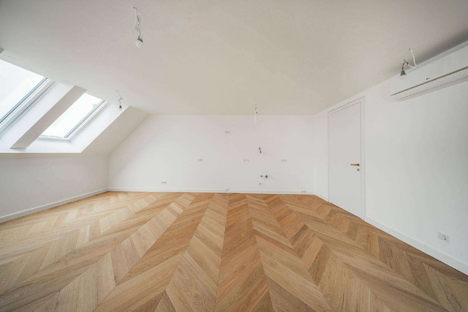 Helles Zimmer mit Fischgrätparkett, Dachfenstern, Dachschräge und Klimaanlage für Komfort.