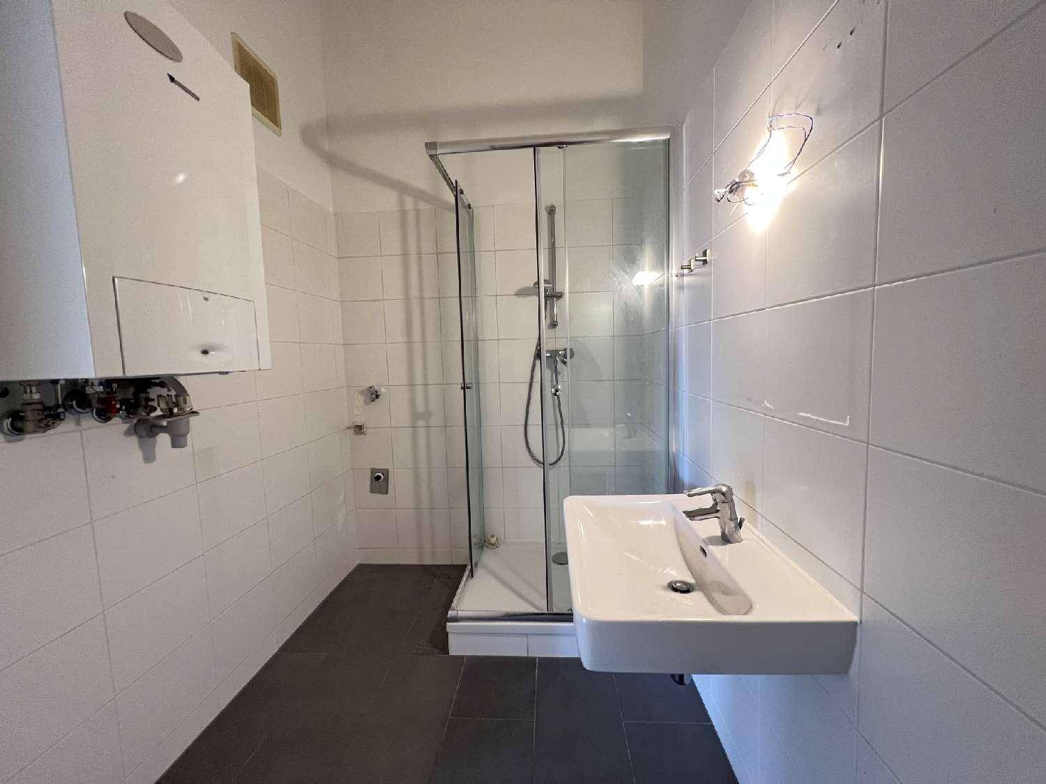 Schlichtes Badezimmer mit Duschkabine, Waschbecken und Heiztherme an der Wand.