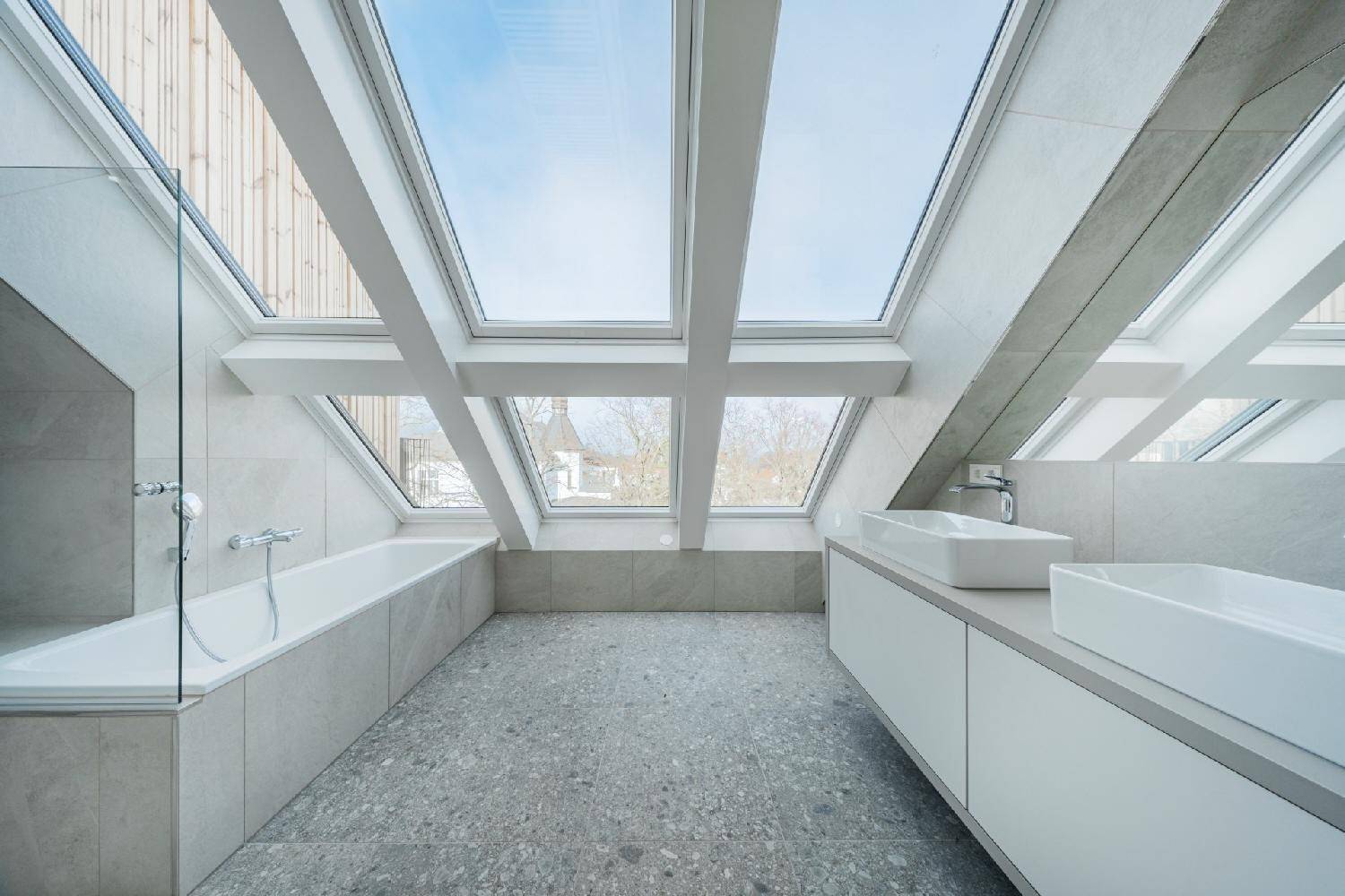 Geräumiges Dachgeschoss-Badezimmer mit Doppelwaschbecken, Badewanne und großen Dachfenstern.