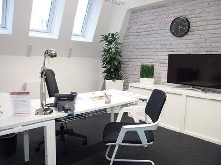 Modernes Büro im Dachgeschoss mit Schreibtisch, Fernseher und schrägen Dachfenstern für viel Licht.