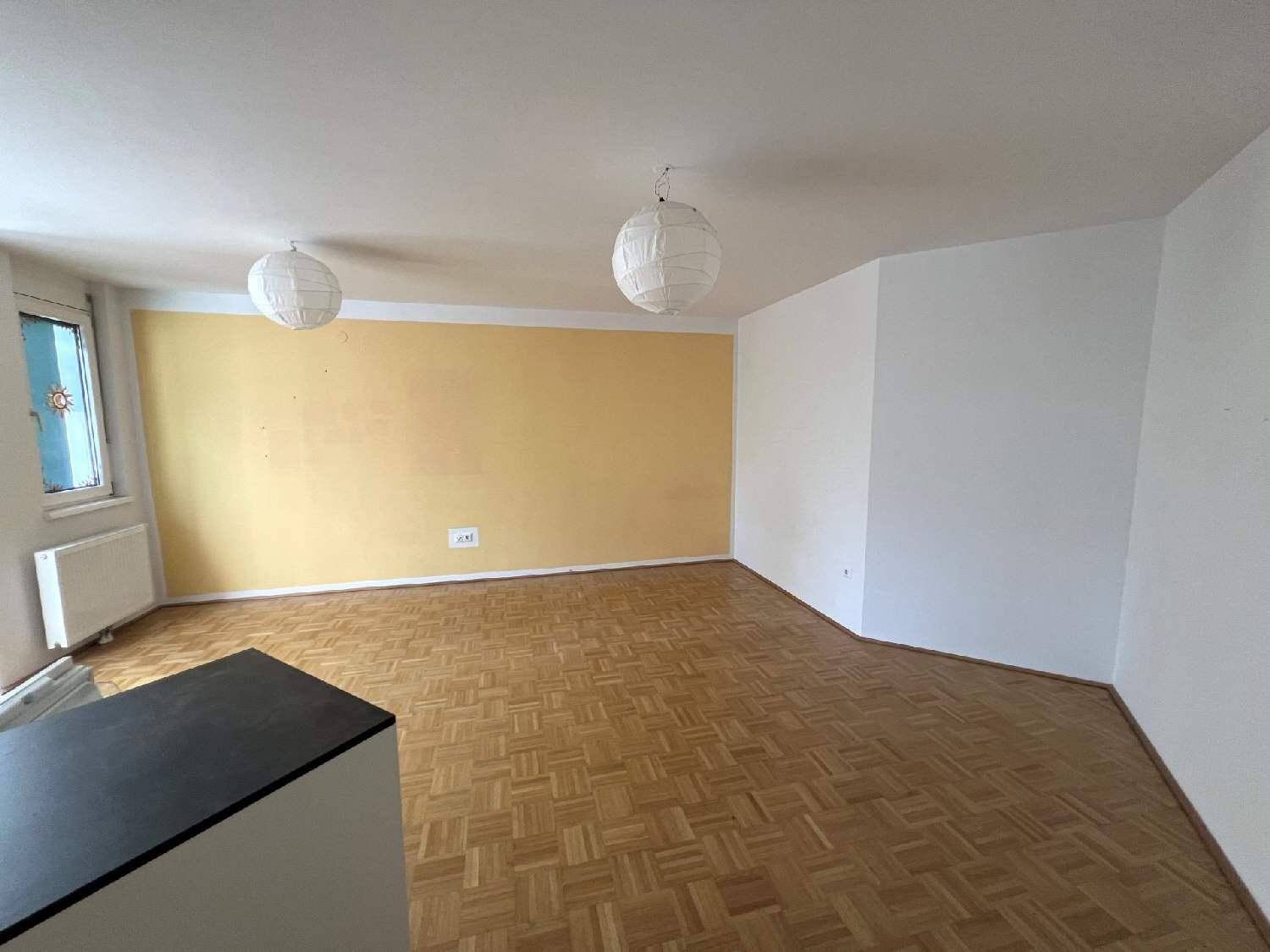 Geräumiges Wohnzimmer mit Fischgrätparkett und einer auffälligen gelben Wand, bereit zur individuellen Gestaltung.