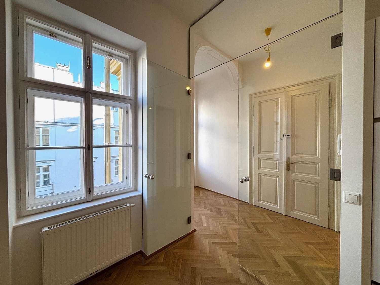 Heller Übergangsbereich mit Fischgrätparkett, Fenster und moderner Glasabtrennung zu weiteren Räumen.
